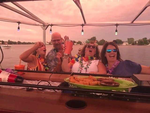 Guests in leis laughing at the bar at sunset